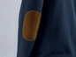 Eine dunkelblaue Jacke mit einem braunen Leder-Ellenbogen-Patch.