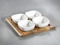 Vier weiße quadratische Schalen auf einem Holztablett.