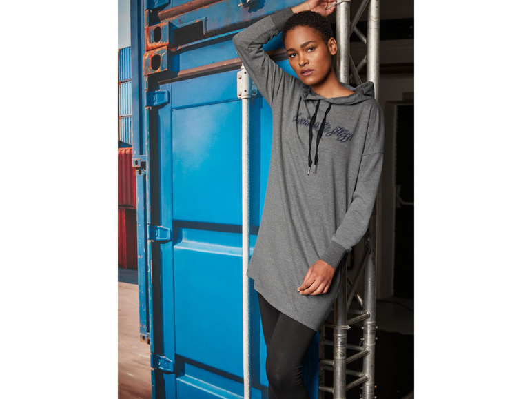 Eine Frau trägt ein graues Kapuzenkleid mit langen Ärmeln.