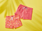 Zwei rosafarbene Shorts für Mädchen, eine mit Sonnenschein-Druck und eine unifarbene.