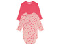 Ein rosafarbenes Babybody mit Herzchenmuster und ein rosafarbenes Langarmshirt.