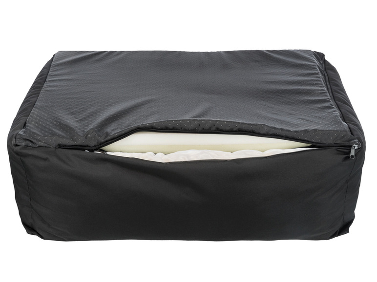 Ein schwarzes Hundebett mit einem offenen Reißverschluss, der eine weiße Schaumstoffmatratze zeigt.