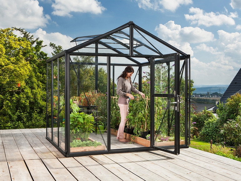 Eine Frau in einem Gewächshaus mit Pflanzen und einer offenen Tür.