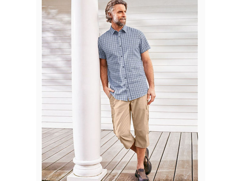 Mann in einem karierten Hemd und beigen Chino-Hosen.