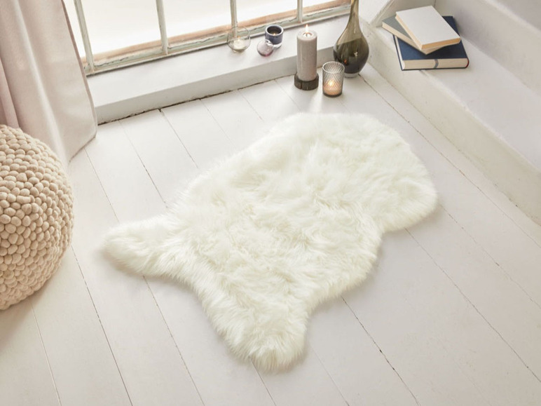 Ein weißer, flauschiger Teppich auf einem Holzboden.