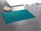 Eine türkisfarbene Badezimmermatte in einem Badezimmer.
