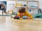 Ein Kind spielt mit LEGO City Fahrzeugen, darunter ein Polizeiauto und ein Monstertruck.