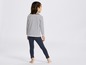 Ein Mädchen trägt ein gestreiftes Shirt und blaue Leggings.