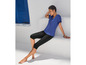 Eine Frau trägt ein blaues T-Shirt und schwarze Capri-Leggings.