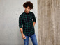 Mann in einem grünen kariert Hemd und blauen Jeans.