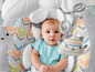 Ein Baby sitzt in einem Fisher-Price Schaukelstuhl mit Spielbogen.