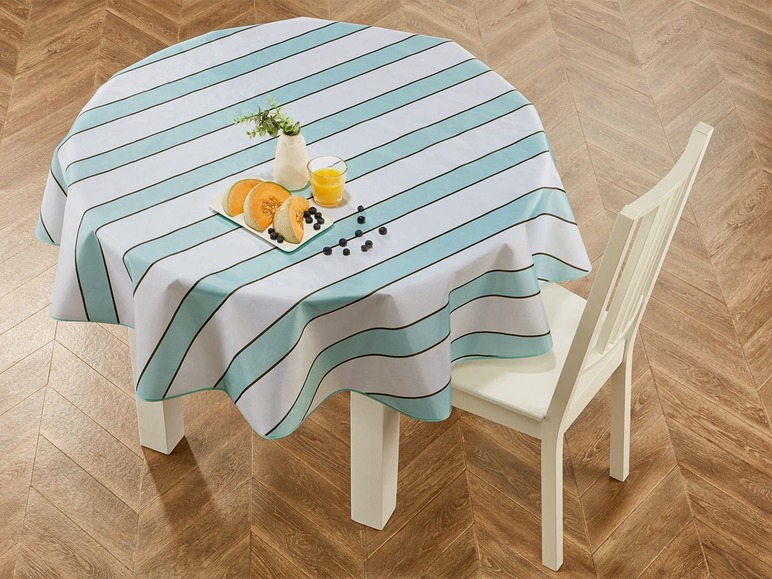Ein gestreiftes Tischtuch mit Früchten und einem Glas Saft auf einem runden Tisch