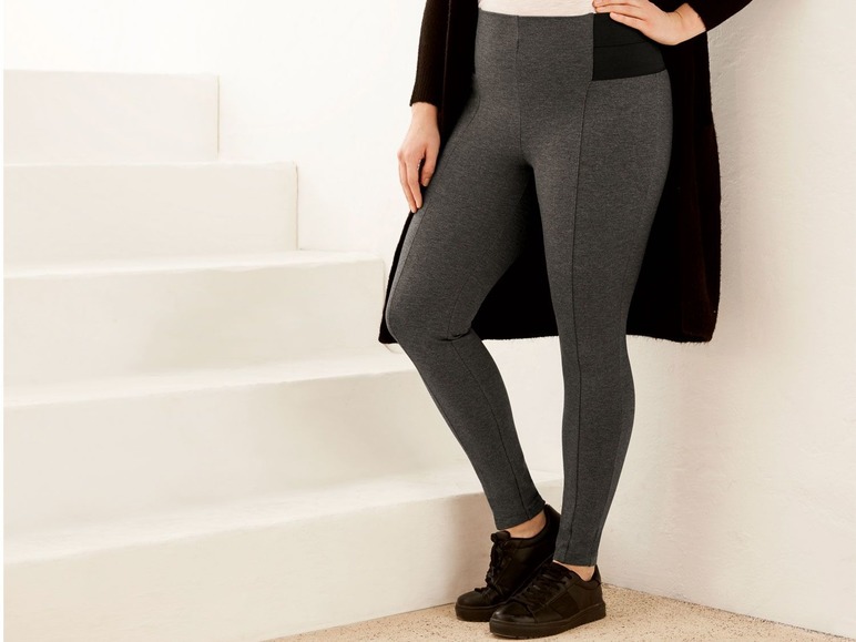 Eine Frau trägt schwarze Leggings und Sneaker auf einer weißen Treppe.
