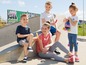 Vier Kinder mit Eis am Stiel und ein Mädchen mit Inline-Skates auf einer Betonrampe.