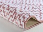 Eine rosa Badematte mit einem weißen geometrischen Muster.
