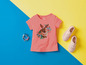 Ein rosa T-Shirt mit Kaninchen-Print, Sneakers und Armbändern.