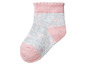 Ein rosa und grauer Babysocken mit Herzen.