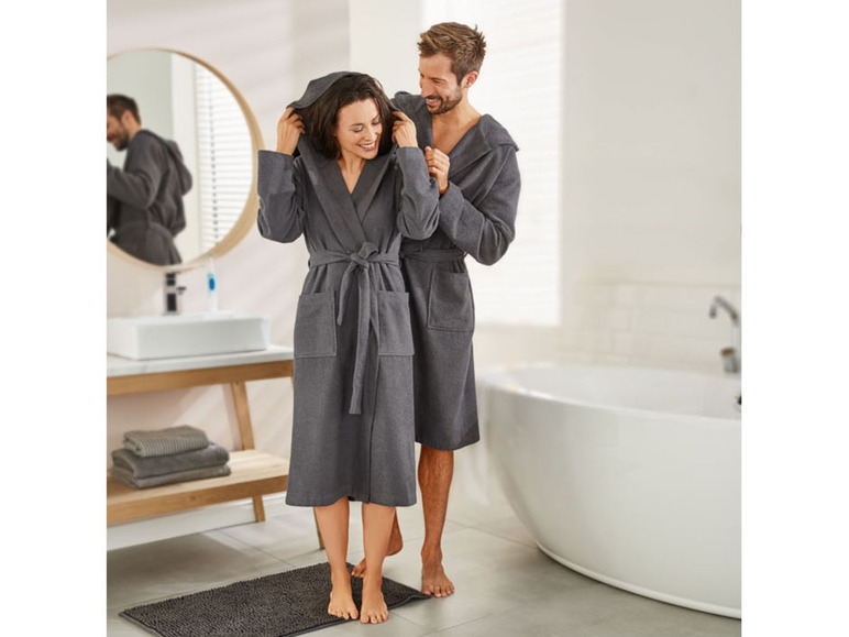 Ein Mann und eine Frau in grauen Bademänteln im Badezimmer.