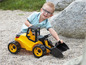 Ein Kind spielt mit einem gelben Spielzeug-Traktor mit schwarzer Schaufel.