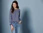 Eine Frau trägt ein gestreiftes Oberteil und Jeans.
