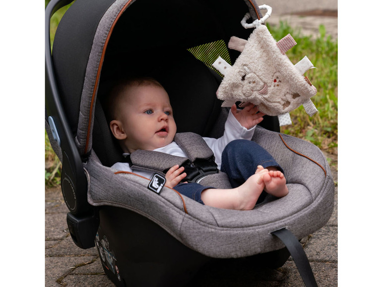 Baby in einem Autositz mit einem Schmusetuch.