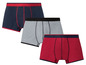Drei Boxershorts in dunkelblau, grau und rot.