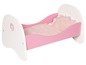 Ein rosafarbenes Holz-Babybett mit Kissen und Decke.
