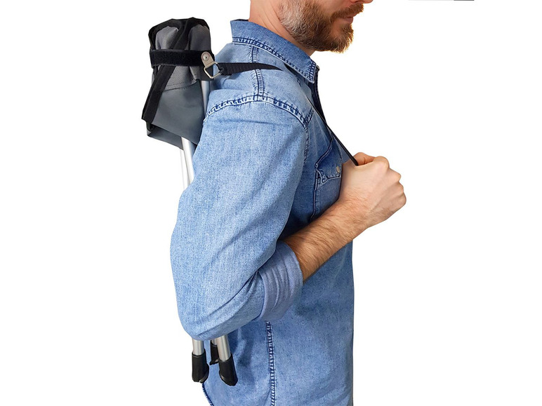 Ein Mann trägt einen zusammenklappbaren Campingstuhl auf dem Rücken.