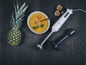 Ein weißer Stabmixer von Grundig, eine Schüssel mit Suppe und eine Ananas.