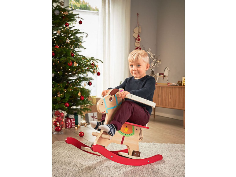 Ein Kind reitet auf einem Holzpferd zu Weihnachten.