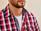 Ein Mann trägt ein rot-weiß-blaues kariertes Hemd.