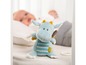 Ein blauer Plüschdrache von Fehn mit gestreiftem Bauch, in einem Babybett mit einem Baby.