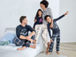 Eine Familie im Schlafanzug, mit einem Mann in einem dunkelblauen Shirt mit dem Aufdruck 'True Quality'.