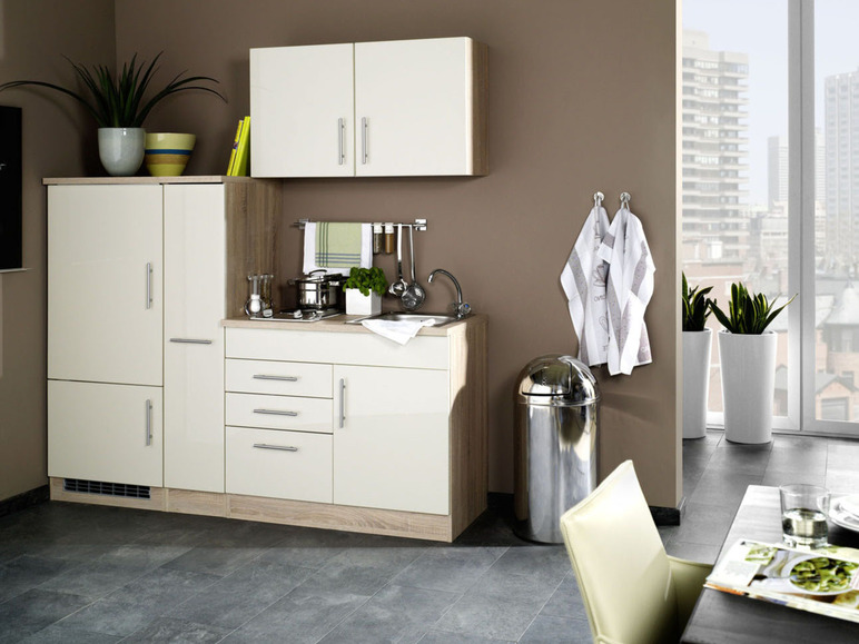 Eine weiße Küche mit Kühlschrank, Arbeitsplatte und Schränken.