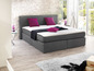 Ein graues Boxspringbett mit rosa Kissen