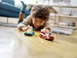 Ein Junge spielt mit zwei LEGO-Rennwagen auf dem Boden.