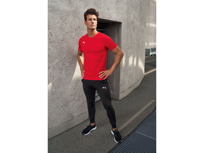Mann in rotem Puma T-Shirt und schwarzen Jogginghosen.