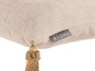 Beige Kissen mit Quaste und Magma-Etikett.