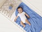 Baby in einem Babybett mit einer blauen Decke.
