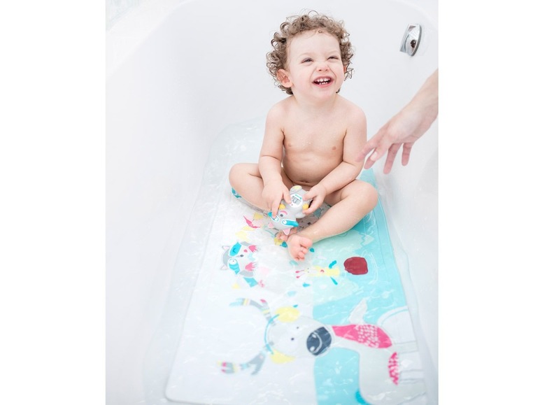 Ein Baby spielt in der Badewanne mit einer Badematte und Spielzeug.