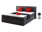 Ein graues Boxspringbett mit roten Kissen