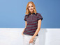 Eine Frau trägt ein gestreiftes Poloshirt und weiße Hosen.