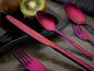 Ein rosafarbenes ECHTWERK-Messer, Löffel und Gabel auf schwarzem Untergrund.