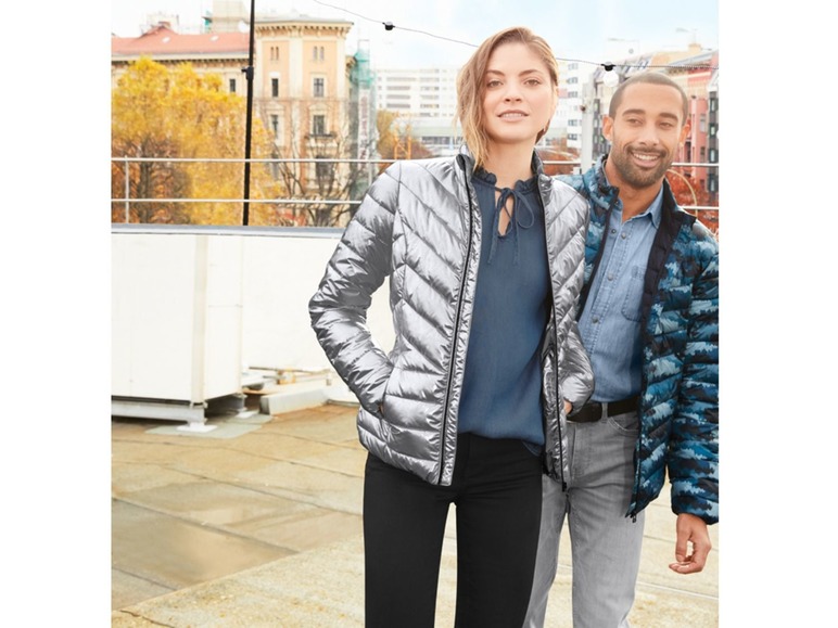 Eine Frau und ein Mann tragen Winterjacken auf einem Dach.