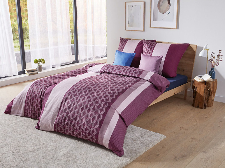 Ein rosafarbenes und violettes Bettbezug mit geometrischem Muster.