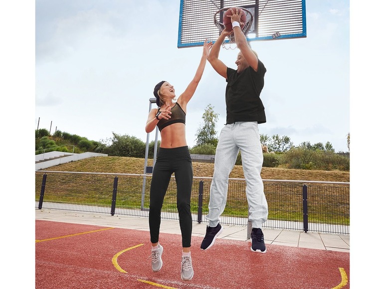 Ein Mann und eine Frau spielen Basketball in Sportkleidung.