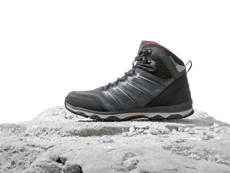 Schwarzer Wanderschuh mit roten Akzenten auf einem steinigen Untergrund.