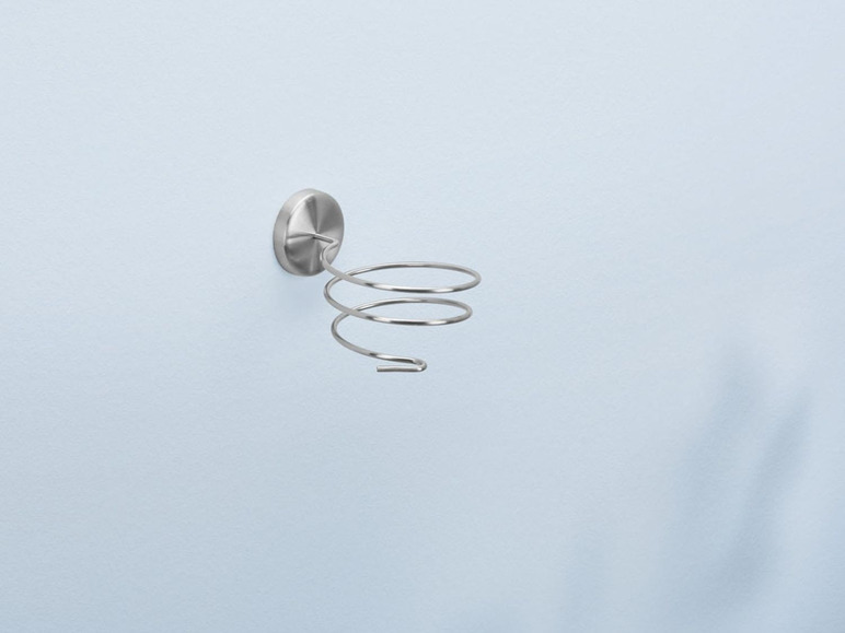 Ein silberner Föhnständer mit Spiralform an der Wand befestigt.