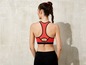 Eine Frau trägt einen roten Sport-BH und schwarze Leggings.