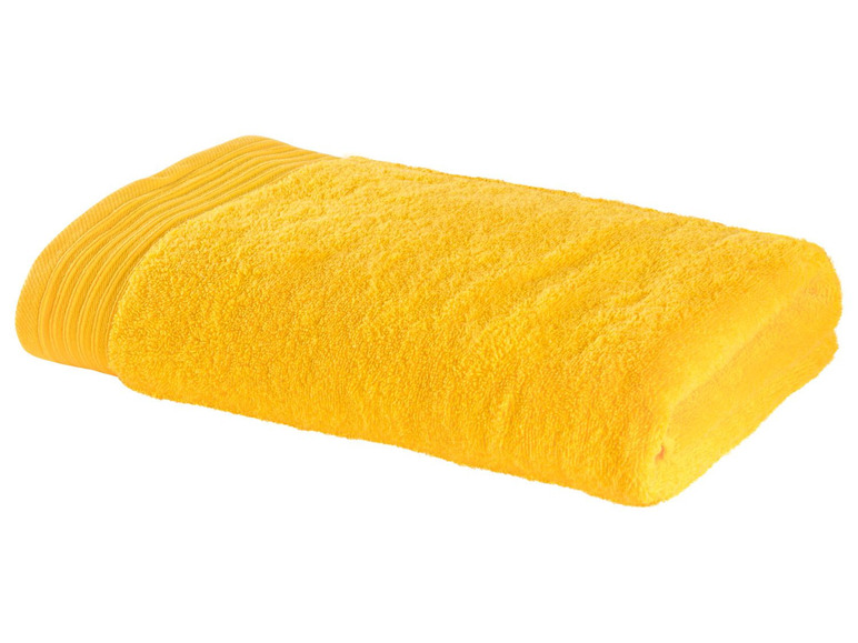 Ein gelbes Handtuch auf weißem Hintergrund gefaltet.